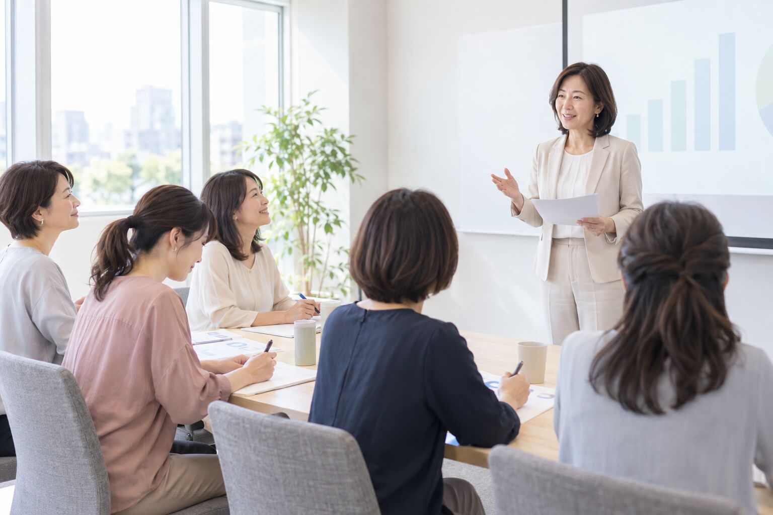 明るいセミナールームで、講師の話を聞きながらメモを取る女性たち